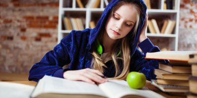 Woman Wearing Blue Jacket Sitting on Chair Near Table Reading Books